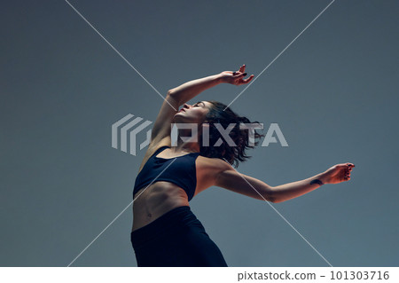 Sportive young woman with relief, slim, fit body in sportswear training against grey studio background 101303716