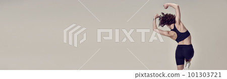 Full-body training. Athletic young woman in sportswear training against grey studio background. Dynamics and motion 101303721