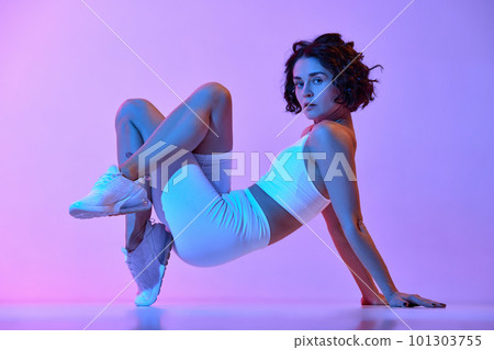 Endurance. Young sportive woman in comfortable sportswear training against gradient pink blue background in neon light 101303755