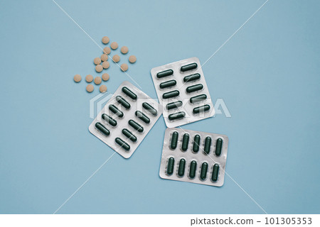 Tablets in capsules and herbal tablets on a blue background Tablets in capsules and herbal tablets on a blue background 101305353