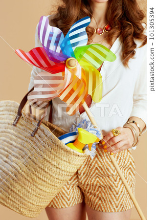 Elegant woman in blouse and shorts with windmill toy on beige 101305394