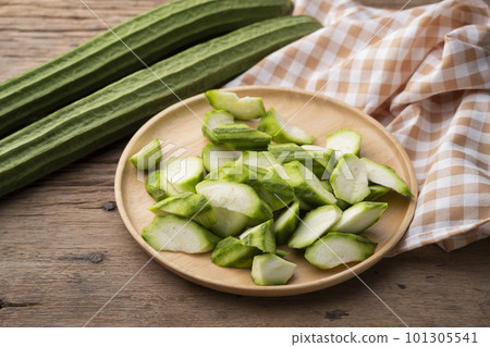 Sliced Fresh Angled luffa (Ribbed Gourd) fruits on wooden bowl Sliced Fresh Angled luffa (Ribbed Gourd) fruits on wooden bowl 101305541