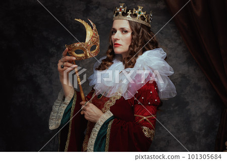 medieval queen in red dress with venetian mask 101305684