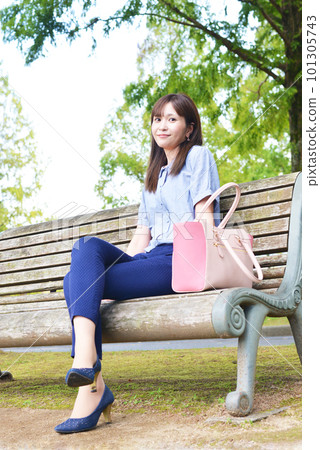 A woman sitting on a park bench 101305743