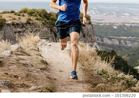rangy male runner run on mountain trail, muscular legs man jogger athlete running narrow path rangy male runner run on mountain trail, muscular legs man jogger athlete running narrow path 101306220