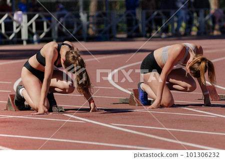 two female athletes low start running 100 meters in track stadium, summer athletics championship 101306232