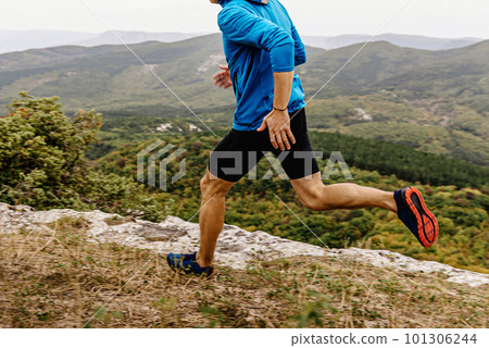 male runner in windbreaker and tights running along precipice, man jogger athlete run mountain trail male runner in windbreaker and tights running along precipice, man jogger athlete run mountain trail 101306244