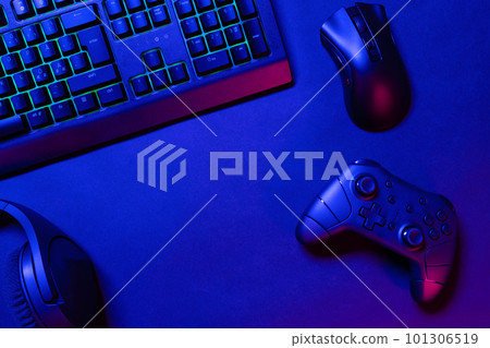 Green lit keyboard on blue lighted gaming gadgets on desk 101306519