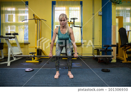 Athletic blonde in gym lifts barbell without load Athletic blonde in gym lifts barbell without load 101306930