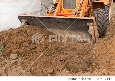 Excavator or bulldozer bucket flattens the ground or road in the industrial zone or construction site Excavator or bulldozer bucket flattens the ground or road in the industrial zone or construction site 101307112