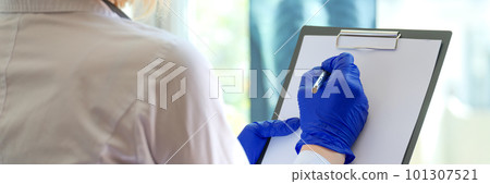 Practitioner with clipboard filling form of patient or writing description of xray 101307521