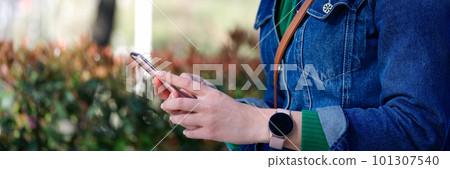 Woman in sunglasses relaxing in park and surfing internet on modern cellphone 101307540