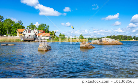 Sunny day in a small village bay on Vaxholm Island. On the coast is the Hembygdsgard Museum and a tranquil terrace with seating areas for guests. Stockholm Archipelago, Sweden Sunny day in a small village bay on Vaxholm Island. On the coast is the Hembygdsgard Museum and a tranquil terrace with seating areas for guests. Stockholm Archipelago, Sweden 101308563