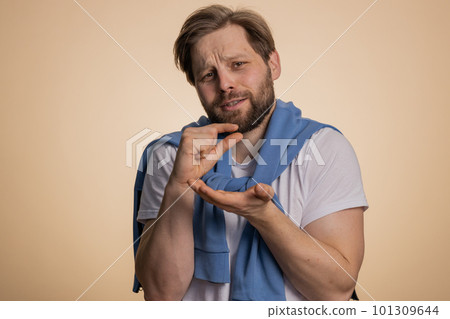 Young man showing a little bit gesture with sceptic smile showing minimum sign measuring small size 101309644