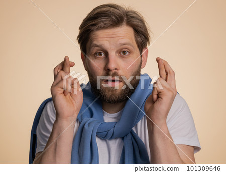 Young man crossed fingers looking at camera asking for good luck news dreaming about win victory 101309646
