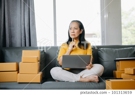 Startup small business SME, Entrepreneur owner Senior woman using smartphone or tablet taking receive and checking online purchase shopping order to preparing pack product box. 101313659