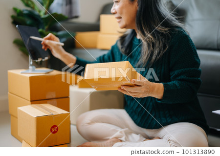 Startup small business SME, Senior woman hand using smartphone or tablet taking receive and checking online purchase shopping order to preparing pack product box. business online shopping concept 101313890