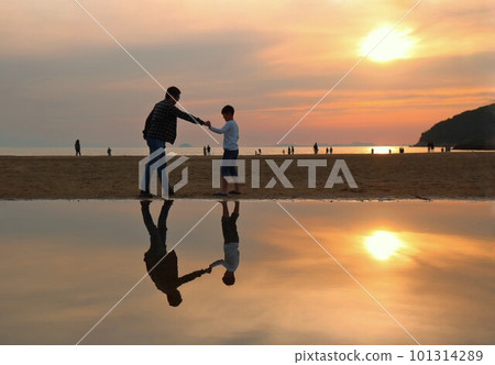 Father and son imitating goo punch on the beach at sunset 101314289