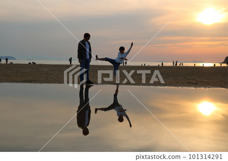 Son and father mimicking martial arts kicks on the beach at sunset Son and father mimicking martial arts kicks on the beach at sunset 101314291