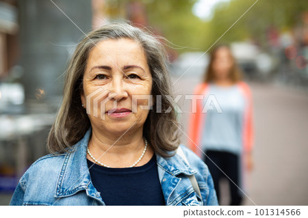 Portrait of positive elderly woman walking along city street Portrait of positive elderly woman walking along city street 101314566