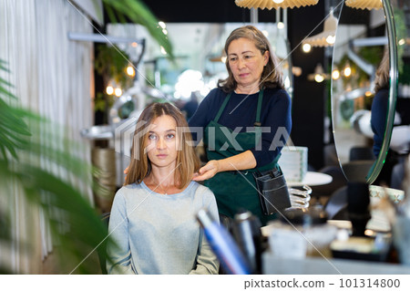 Aged female hairdresser offering modern hairstyling to young woman 101314800