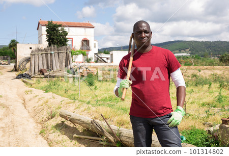 Confident african american male stands against the background of farmhouse 101314802