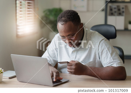 Young african american man using laptop hold credit bank card. banking application, online shopping concept Young african american man using laptop hold credit bank card. banking application, online shopping concept 101317009