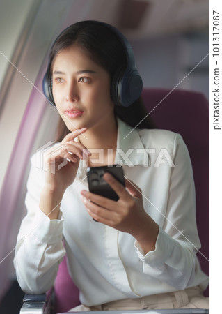 Beautiful Asian business woman listen music by mobile phone during flight in aeroplane. working, travel, business concept 101317087