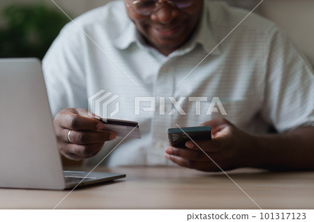 Young african american man using mobile cell phone hold credit bank card. banking application, online shopping concept Young african american man using mobile cell phone hold credit bank card. banking application, online shopping concept 101317123