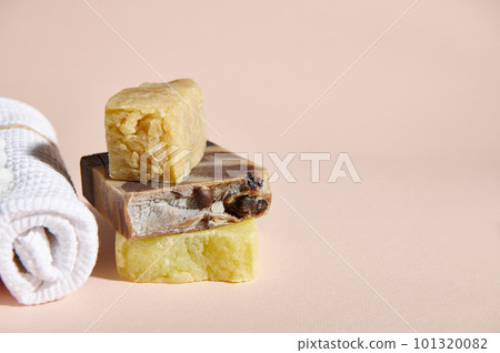 Still life with a stack of cold pressed handmade soap bars and dry shampoos with organic natural ingredients and white terry towel, isolated on pink background. Hygiene and purity, body care concept 101320082