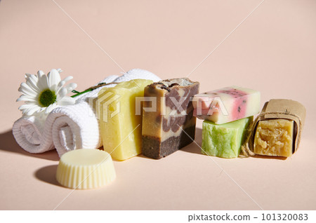 Handmade organic soap bars, solid dry shampoos with natural ingredients and white terry towel, isolated on pink background. Still life. Hair, skin and body care concept. Home spa, hygiene and purity 101320083