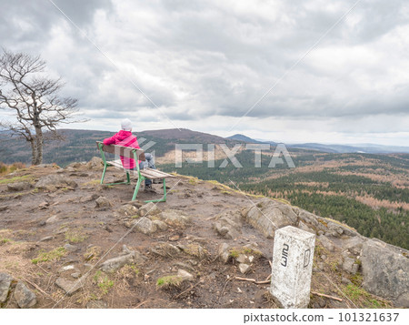 Woman on bench at Lusitian peak in pink warm jacket 101321637