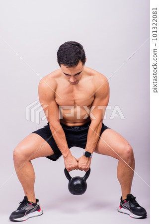 Hispanic male athlete working out with kettlebell on grey background. Crossfit workout theme. 101322081