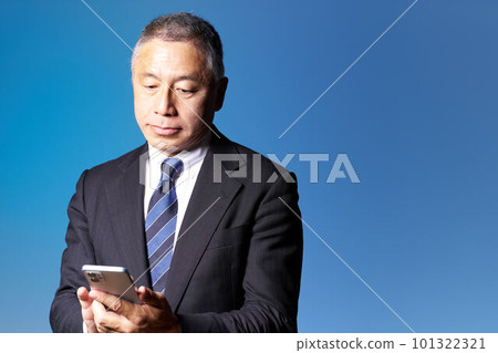 中高級商人檢查智能手機藍背商業形象 中高級商人檢查智能手機藍背商業形象 101322321