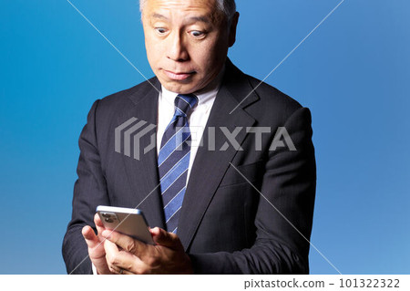 中高級商人用驚訝的表情檢查他的智能手機 藍背商業形象 101322322
