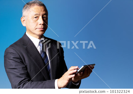 一位中年商人拿著智能手機看著他的藍背商業形象 101322324