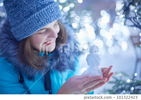 Attractive young female in winter clothes models figure from snow, being in good mood as walks during frosty winter weather, believes in miracle, waits for coming New Year and Christmas holidays 101322423
