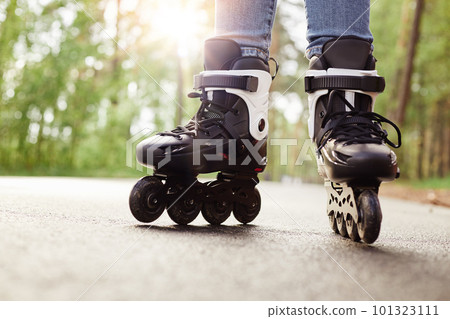 Close up view of unknown person rollerblading in park on sunny day, being on road, spending time in fresh air, enjoying hobby during vacation, fun free time activity. People and lifestyle concept. 101323111