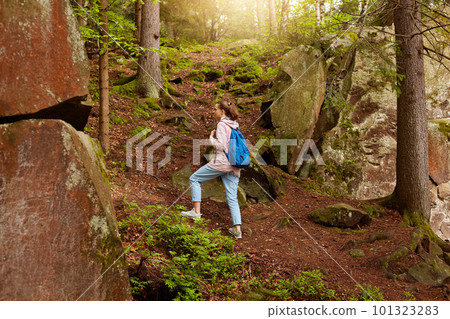 Outdoor shot of wandering energetic female, going on top of forest hill, having holidays, spending time in summer forest, being fond of nature, choosing right path to move. Wanderlust concept. 101323283