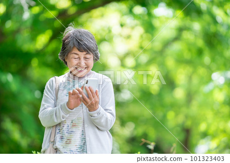 A senior woman who operates a smartphone, an old woman who touches a smartphone outdoors 101323403