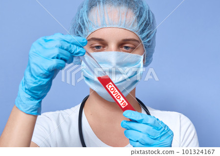 Scientist holding Coronavirus covid-19 infected blood sample tube, young woman testing of blood in laboratory with blood sample collection tubes, doctor wearing disposable hat, gloves and medical mask 101324167