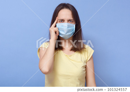 Horizontal portrait of confident conscious young female wearing antibacterial mask, being infected, looking directly at camera, standing isolated over blue background in studio. Covid19 concept. 101324557
