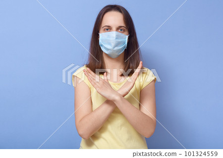 Portrait of conscious serious patient crossing arms, keeping distance from infected people, being in quarantine, wearing protective mask, looking directly at camera. Coronavirus outbreak concept. Portrait of conscious serious patient crossing arms, keeping distance from infected people, being in quarantine, wearing protective mask, looking directly at camera. Coronavirus outbreak concept. 101324559