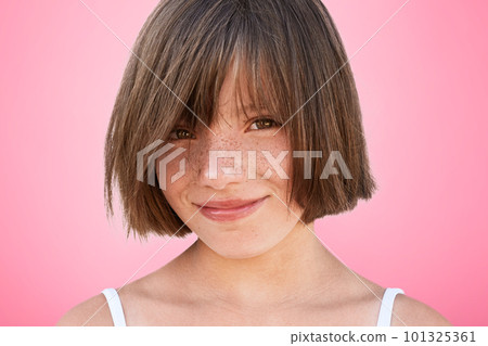 Glad delightful smiling cheerful little kid with bobbed hairstyle looks happily at camera, rejoices spending free time with parents who bought her new toy. Pretty adorable girl poses in studio 101325361