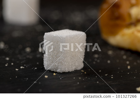 Refined sugar pieces on a black slate board Refined sugar pieces on a black slate board 101327266