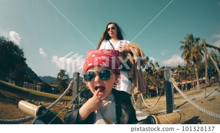 Adorable little baby girl in cool biker outfit rides the tricycle guided by her mother Adorable little baby girl in cool biker outfit rides the tricycle guided by her mother 101328137