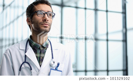 a young doctor stands alone in the studio and poses for the camera 101329102