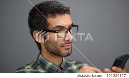 positive young male holding smartphone, chatting in social network with friends 101329157