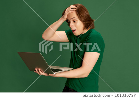Disappointed salesman trying to understand what happening, holding laptop with questioning facial expression over green background Disappointed salesman trying to understand what happening, holding laptop with questioning facial expression over green background 101330757