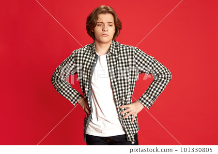 Young man, guy wearing white t-shirt standing with dislike face and hands on belt over red background. Unpleasant emotions Young man, guy wearing white t-shirt standing with dislike face and hands on belt over red background. Unpleasant emotions 101330805